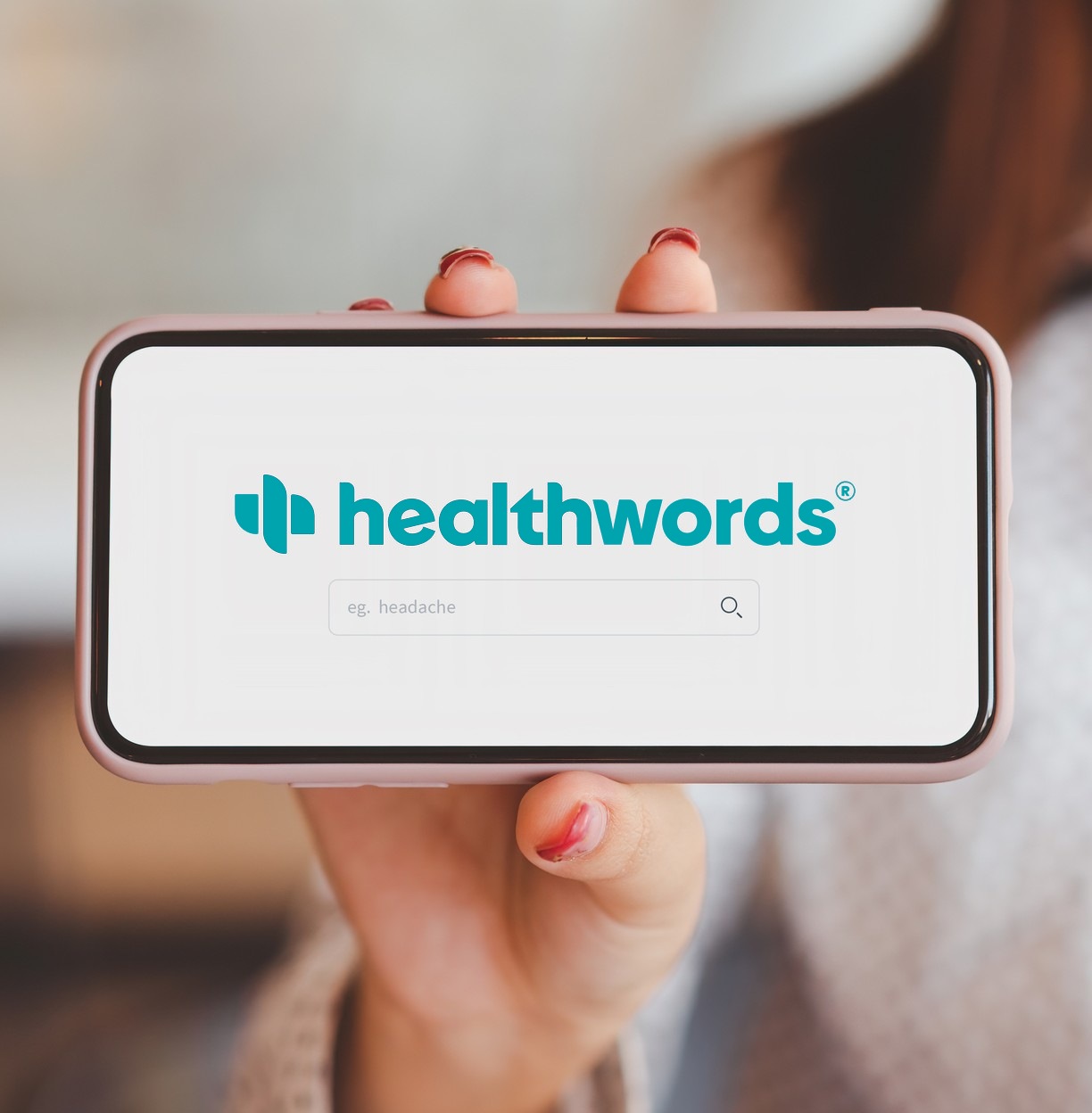 A hand holding up a phone with the Healthwords home screen.