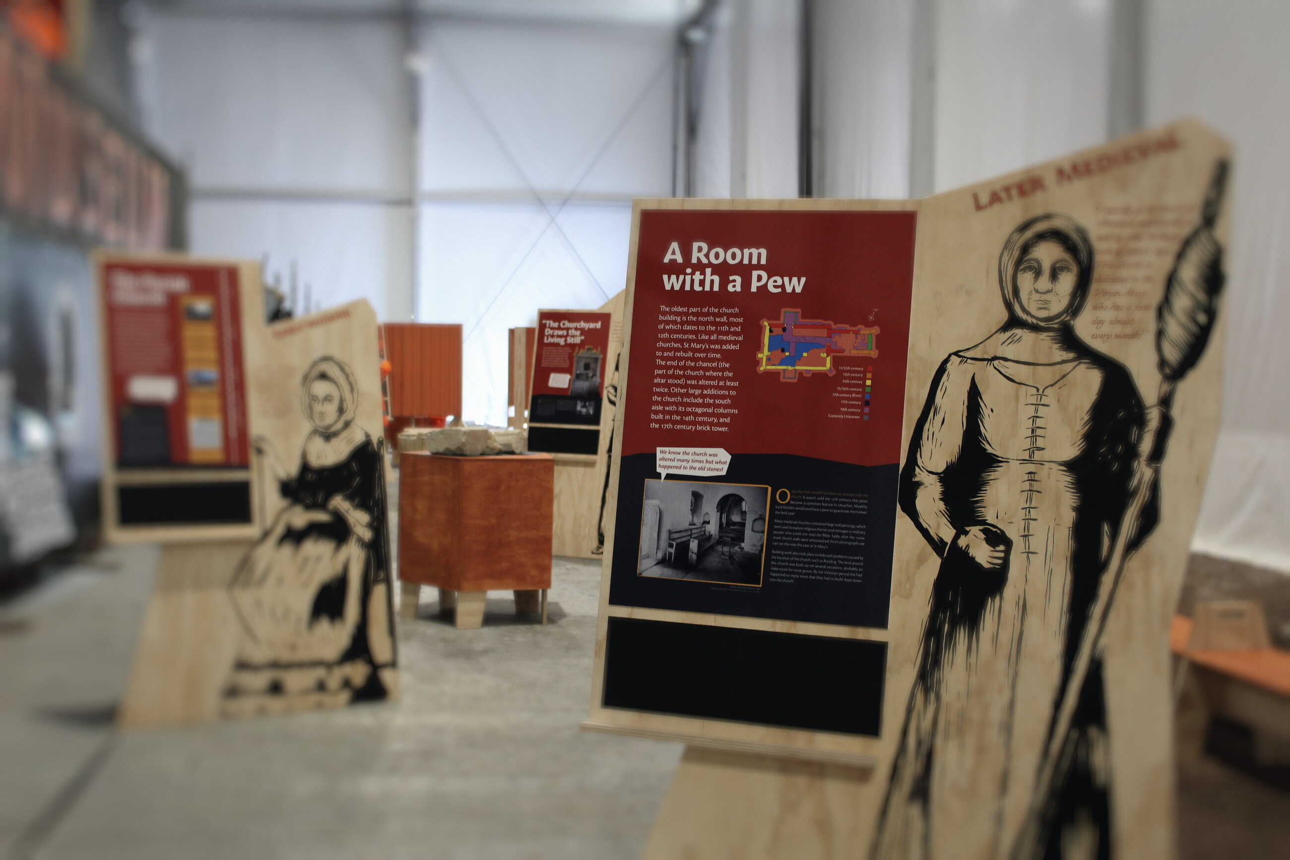 Inside the museum, plywood character stands and A Room with a Pew panel.